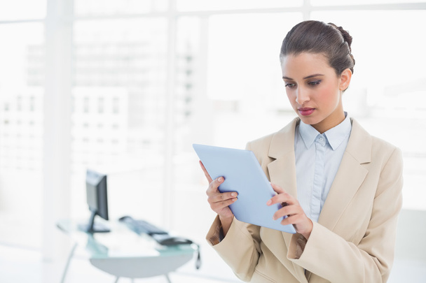 Stern businesswoman looking at a tablet pc - Foto, Imagen