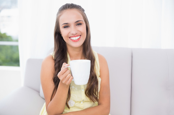 Cheerful young brunette holding a mug - Фото, изображение