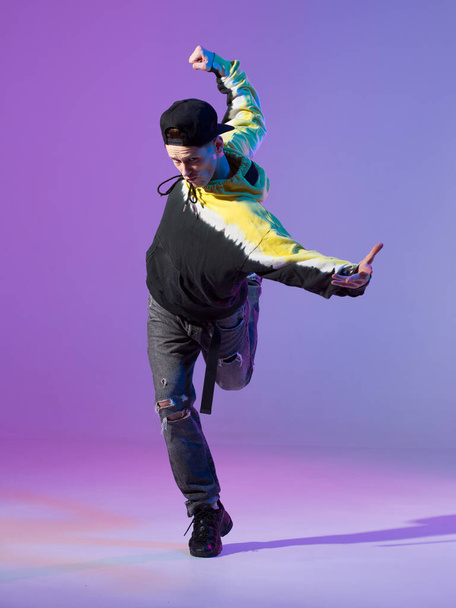 Breakdancing young man in hoodie and baseball cap. Dance school poster. Copy space. Battle competition announcement. - 写真・画像