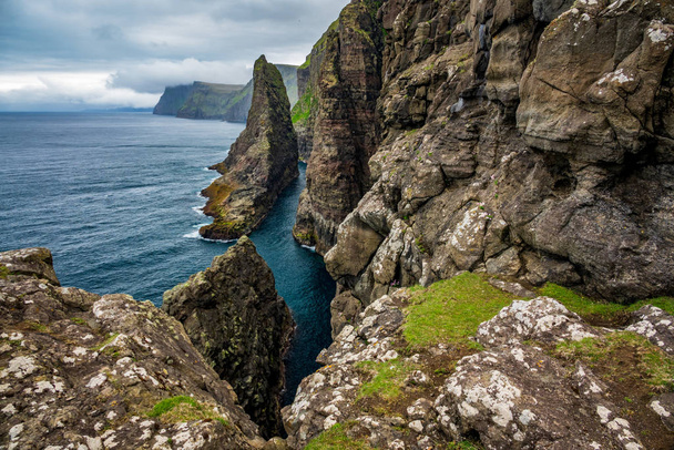 Costa íngreme das Ilhas Faroé com grandes pedregulhos
 - Foto, Imagem