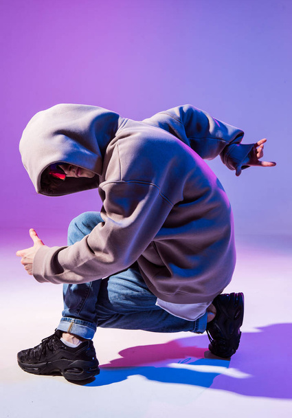 Breakdancing young man in hoodie with hair styling. Dance school poster. Copy space. Battle competition announcement. - 写真・画像