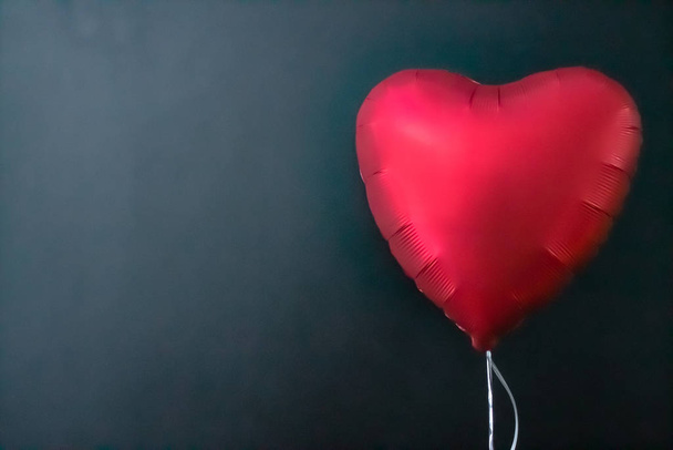 Червоні повітряні кулі у формі серця на чорному тлі. День валентинки, любов
. - Фото, зображення