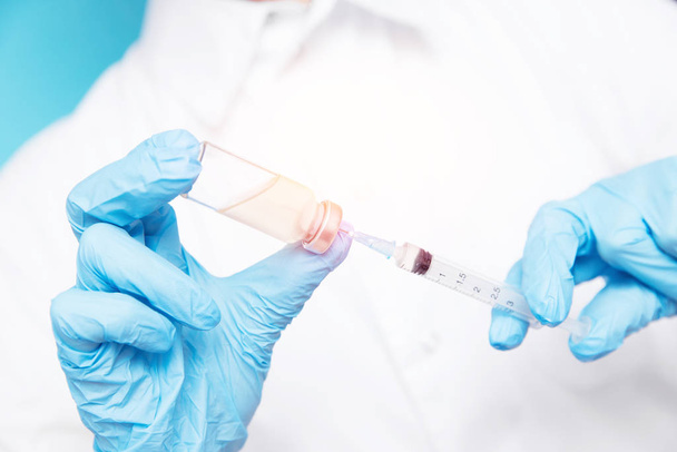 Médico mão segurando seringa e vacina em luvas azuis casaco branco. Conceito de injeção de doença
 - Foto, Imagem