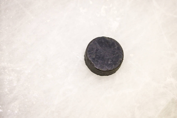 Чорний льодовий хокейний каучук, розташований на арена ковзанки. Льоду і
 - Фото, зображення