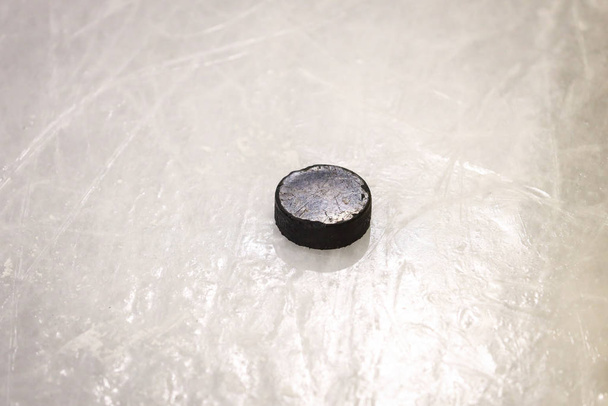 Černý hokejový gumový puk umístěný na kluzišti arény. Led a - Fotografie, Obrázek