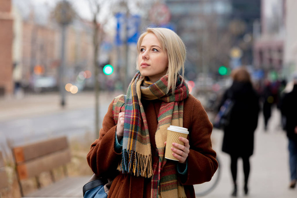 Mooie blonde vrouw met kopje koffie op straat - Foto, afbeelding