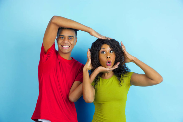 Young emotional african-american man and woman on blue background - Фото, зображення