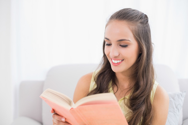 Smiling young brunette reading a book - Fotó, kép