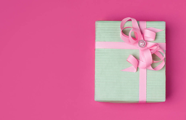 δώρο σε συσκευασία περιτυλίγματος χρώματος μέντας με ροζ κορδέλα σε ροζ φόντο με χώρο αντιγραφής. - Φωτογραφία, εικόνα