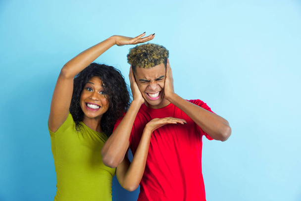 Young emotional african-american man and woman on blue background - Foto, Imagen
