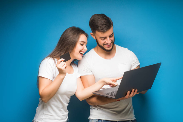 Portrait of happy young couple against blue background - Foto, imagen