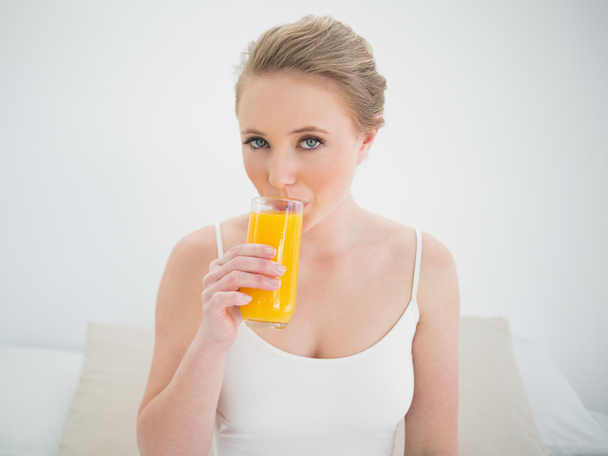 Natural content blonde drinking a glass of orange juice - Foto, afbeelding