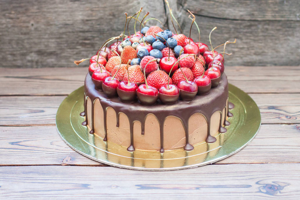 Chocolate cake with melted dark chocolate and fresh strawberries, blueberries and cherries on top. - Fotoğraf, Görsel