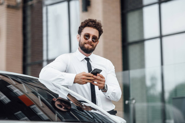 Handsome young businessman near new white car, selective focus - Fotó, kép