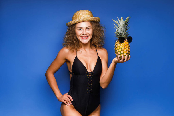 Joyful curly hair woman holding fresh pineapple with sunglasses  - Foto, Imagem