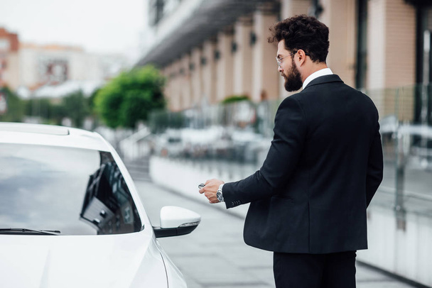 Όμορφος νέος επιχειρηματίας κοντά στο νέο λευκό αυτοκίνητο, επιλεκτική εστίαση - Φωτογραφία, εικόνα