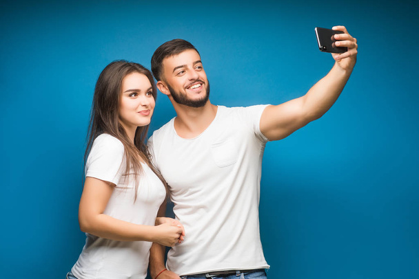 Portrait of happy young couple against blue background - Photo, Image