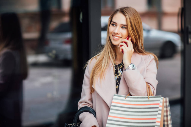 Beautiful young blonde woman with shopping bags, selective focus - Фото, зображення