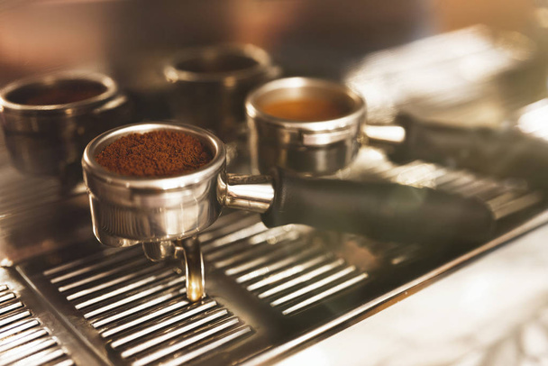 two coffee holders one with ground coffee near professional coffee machine close up, barista tools - Foto, imagen