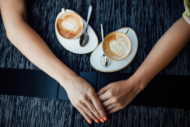 Top view of mother and daughter holding hands near coffee cups - Fotoğraf, Görsel