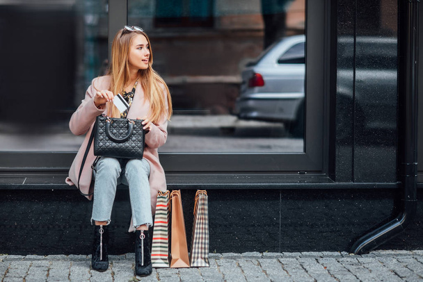 Beautiful young blonde woman with shopping bags, selective focus - Фото, зображення