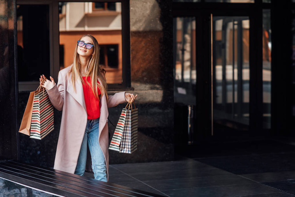 Beautiful young blonde woman with shopping bags, selective focus - Photo, image