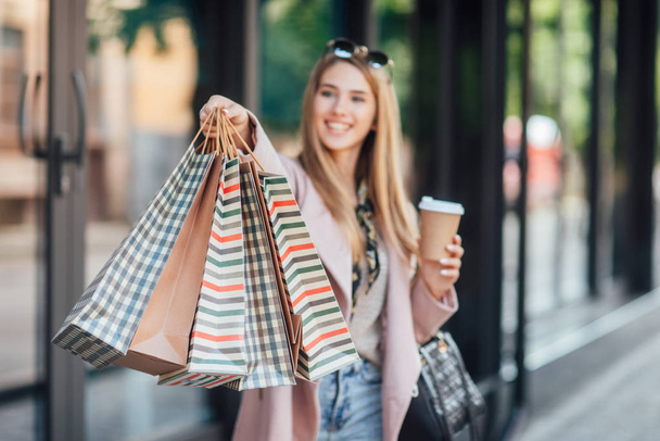 Beautiful young blonde woman with shopping bags, selective focus - Foto, afbeelding