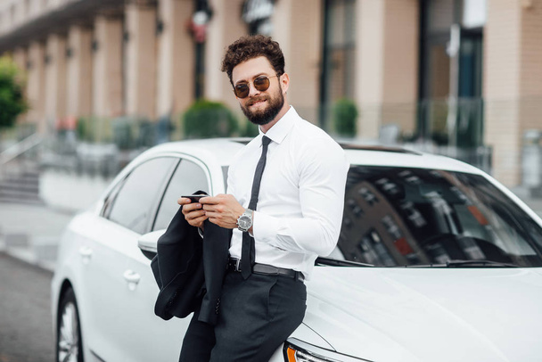 Handsome young businessman near new white car, selective focus - Foto, afbeelding