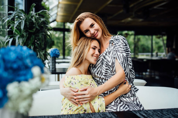 happy beautiful mom and daughter resting on summer terrace cafe  - Foto, Imagen