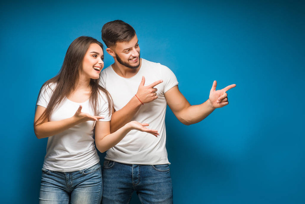 Portrait of happy young couple against blue background - Foto, Imagen