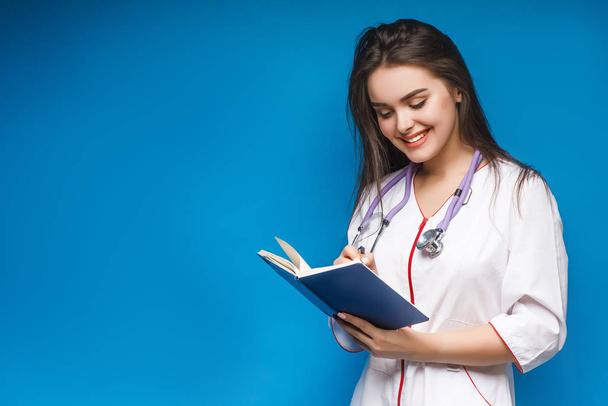 Portrait of young medical assistant on blue background - Valokuva, kuva