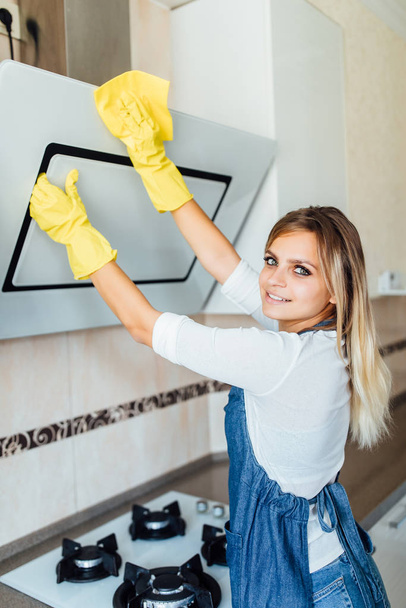 молодая женщина из профессиональной уборки компании уборка на кухне в желтых перчатках
  - Фото, изображение