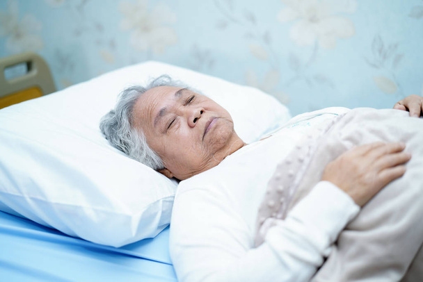 Азиатская пожилая или пожилая старушка улыбается светлым лицом с крепким здоровьем, лежа на кровати в стационаре: здоровая сильная медицинская концепция
 - Фото, изображение