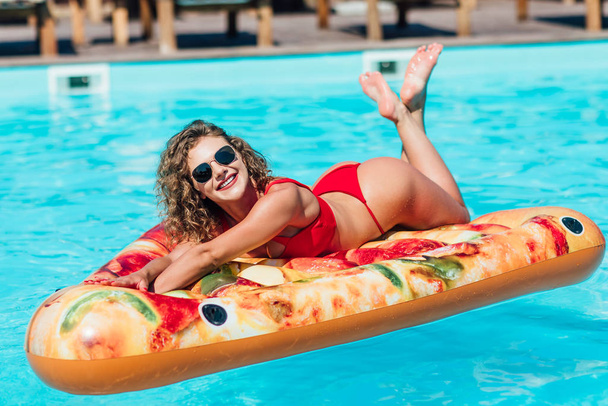 Pretty blonde woman with curly hair relaxing in swimming pool - Photo, image
