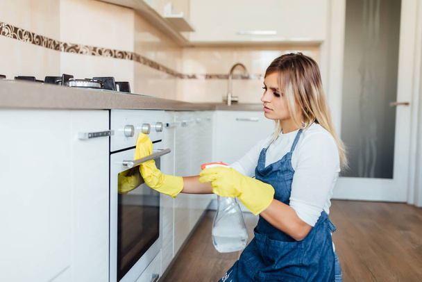 Young woman in yellow gloves cleaning oven, selective focus - Foto, Imagem