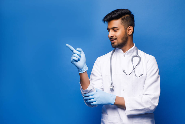 indian male doctor in white coat on blue background - Foto, afbeelding
