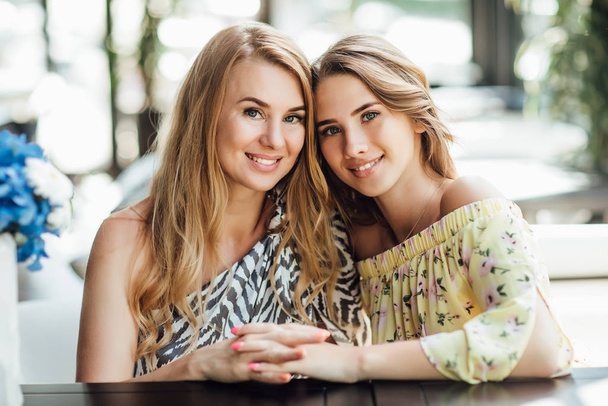 happy beautiful mom and daughter resting on summer terrace cafe  - Foto, imagen