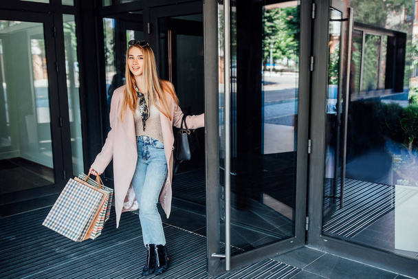 Beautiful young blonde woman with shopping bags, selective focus - Photo, Image