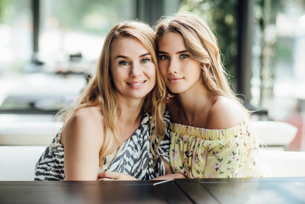 happy beautiful mom and daughter resting on summer terrace cafe  - Foto, afbeelding