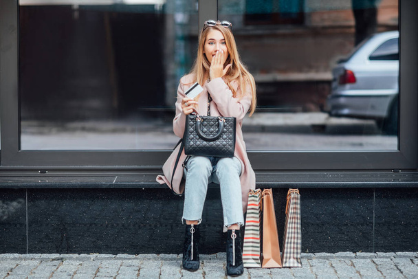 Beautiful young blonde woman with shopping bags, selective focus - Фото, изображение