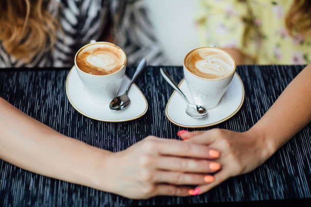 Top view of mother and daughter holding hands near coffee cups - Fotografie, Obrázek