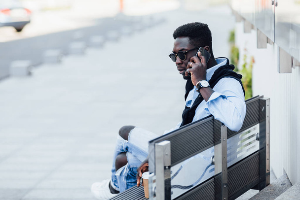 Sokakta telefonla konuşan mutlu Afrikalı serbest yazar.  - Fotoğraf, Görsel