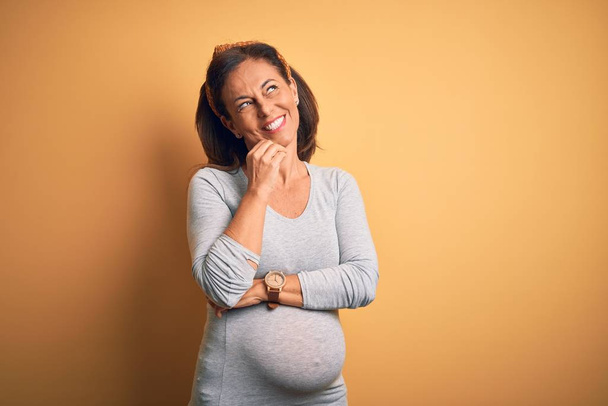 Középkorú terhes nő várandós baba idős terhesség kézzel állon gondolkodás kérdés, töprengő kifejezés. Gondos arccal mosolygott. Kétséges fogalom. - Fotó, kép