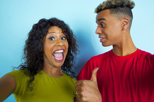 Young emotional african-american man and woman on blue background - Foto, Bild