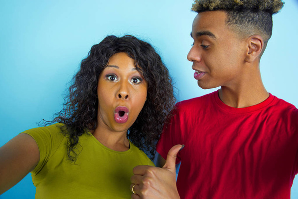 Young emotional african-american man and woman on blue background - 写真・画像