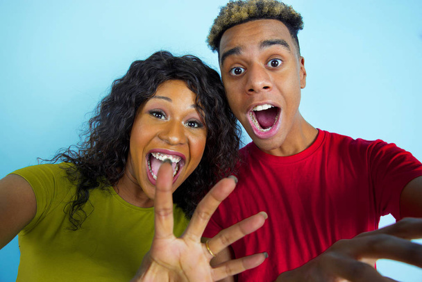 Young emotional african-american man and woman on blue background - Fotó, kép