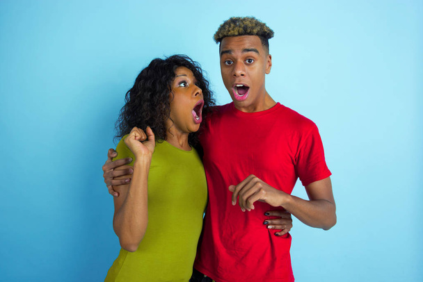Young emotional african-american man and woman on blue background - Zdjęcie, obraz