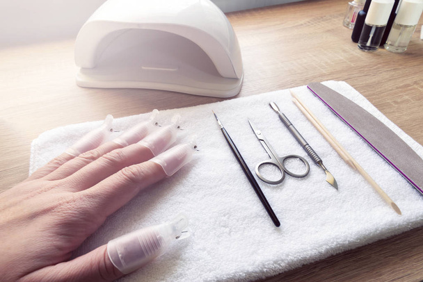 Detailní záběr ženské paže demonstrující proces odstraňování gelového leštidla nůžkami. - Fotografie, Obrázek