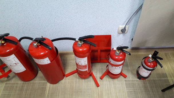 eine Gruppe roter Feuerlöschzylinder steht auf dem Fußboden - Foto, Bild