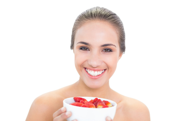 Cheerful young woman holding a bowl of strawberries - Foto, Imagem